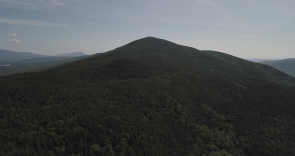 Aerial Drone Shot Flying Over Tree Covered Mountain Towards Summit