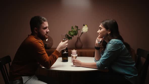 Romantic Young Couple Enjoying Talking and Sitting Together at Dinner Table in Cozy Dark Living Room