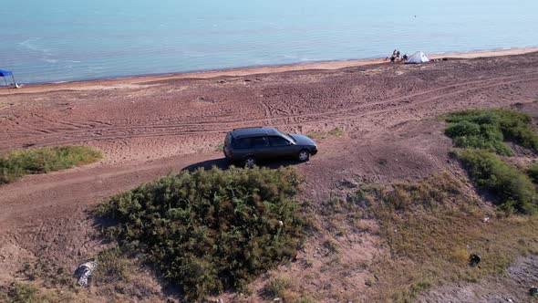 A Black Car is Parked on a Hill Near the Lake