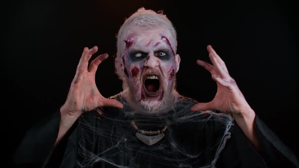 Sinister Man in Costume of Halloween Crazy Zombie with Bloody Wounded Scars Face Trying to Scare