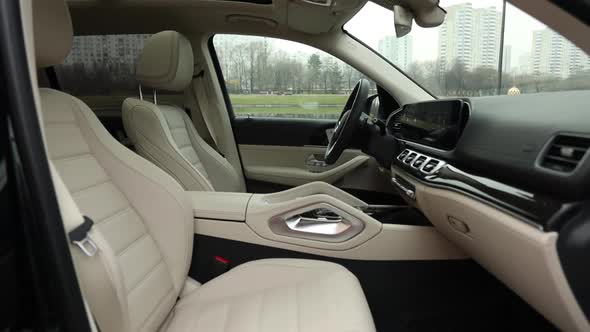 Beige leather interior of a premium SUV with wood trim and a huge multimedia monitor combined