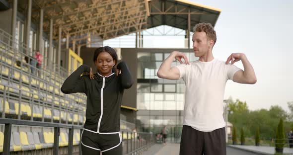 Black Woman and Young Man Warming Up Before Running Outdoors