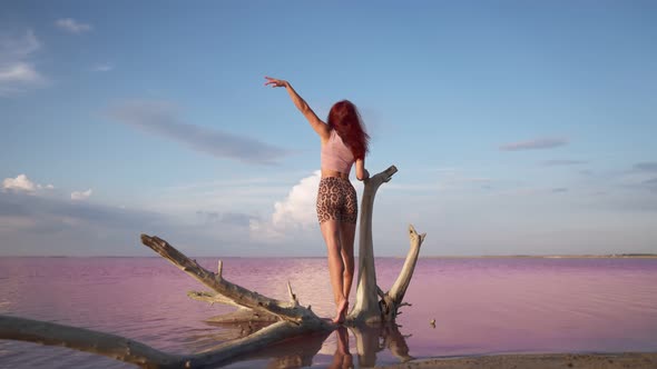 Happy Woman Traveler Raises Hand Up Standing on Background Beautiful Pink Lake