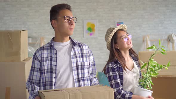 Positive Young Asian Couple with Boxes in Their Hands Moved Into a New Apartment