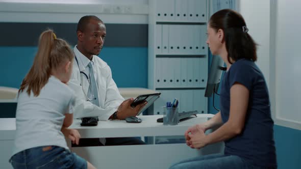 Male Doctor Taking Notes on Tablet at Health Care Consultation