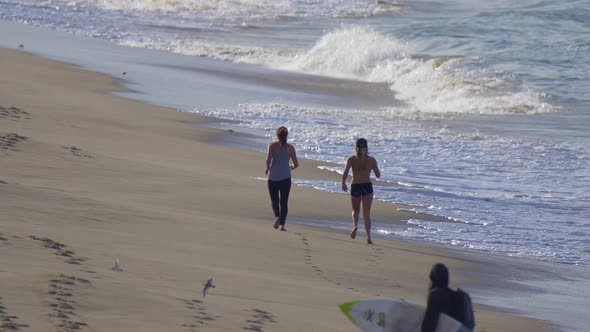 Two women jogging on the beach.