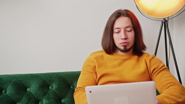 Proud European Freelance Entrepreneur Man Sitting on a Sofa While Working Remotely Using His Laptop