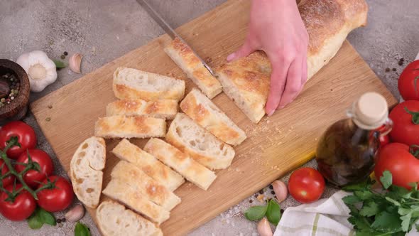 Woman Slicing Baguette on Wooden Cutting Board at Domestic Kitchen