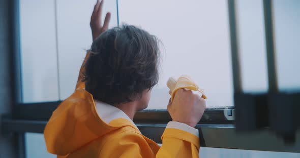Young man looking out of foggy window eating a banana