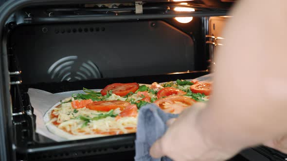Putting pizza in oven. Pizza cooking