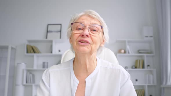 Senior skilled businesswoman with short grey hair greets colleagues waving hand