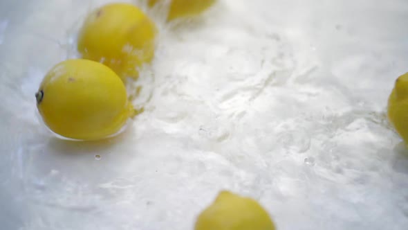 SLOMO of Lemons Falling into Water on White Backdrop