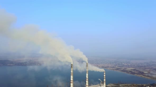 Aerial view of high chimney pipes with grey smoke from coal power plant alt