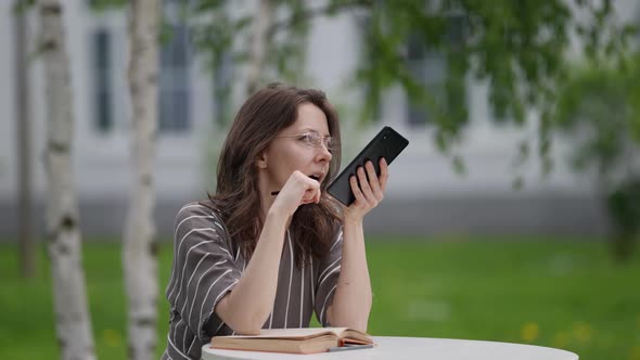 Woman is Using Intelligent Virtual Assistant in Her Smartphone Speaking to Cell Phone