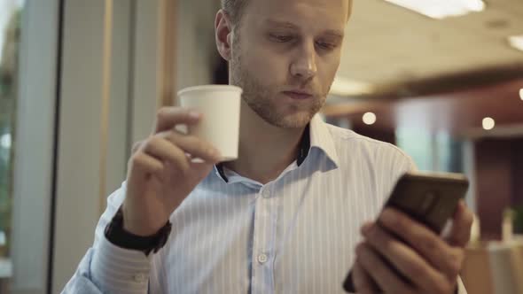 Businessman checking smartphone and driking coffee