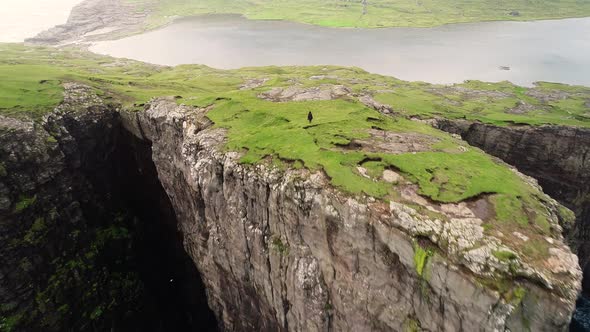 Aerial view of woman walking on the edge of tourists English Slave cliff.