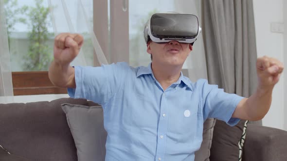 Asian senior older Chinese male happy fun and virtual reality, VR playing games.