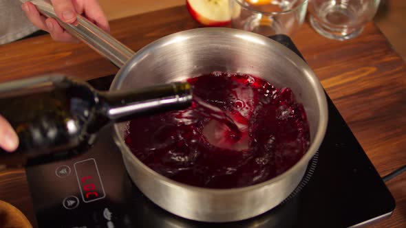 Woman Cooking Mulled Wine Gluhwein with Apples and Oranges Recipe