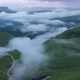 Drone Flight above green fields at the mountains in the clouds and fog. - VideoHive Item for Sale