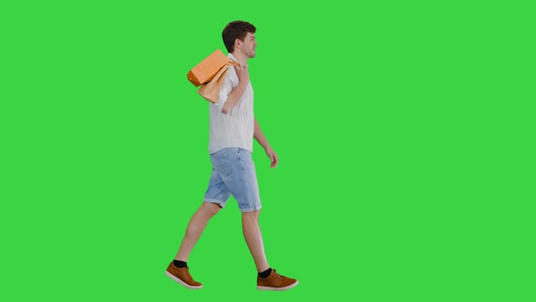 Handsome Man in Casual Clothes Walking with Shopping Bags Looking at Camera on a Green Screen