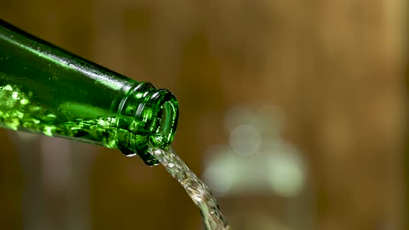 Stream of Cold Fresh Beer Pours From a Green Misted Bottle