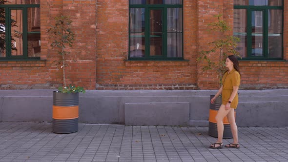 A Woman with a Smile on Her Face Waves Her Hand to a Friend in the Street