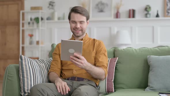 Young Man Talking on Video Call on Tablet on Sofa