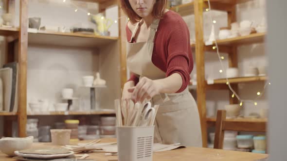 Young Female Potter Patting on Piece of Clay in Workshop