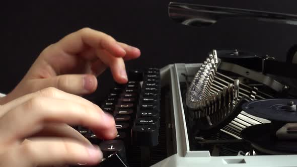 The girl is typing on a retro typewriter.