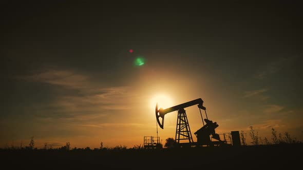 Silhouette of Working Oil Pump From Oil Field at Sunset. The Industrial Equipment