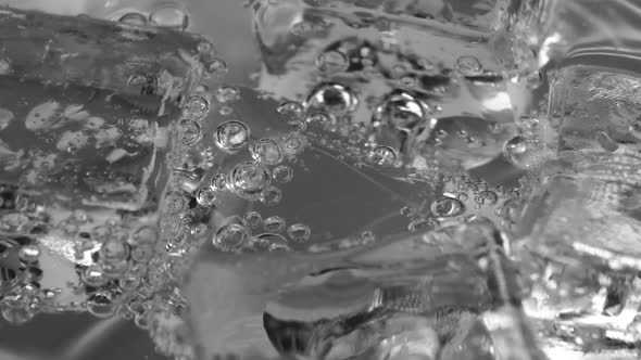 Ice cubes coated with moving bubbles in a clear liquid. Beautiful close-up of alcoholic drinks