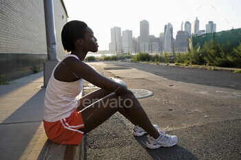 Runner sitting on sidewalk