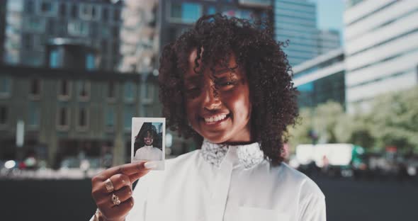 Young african woman smiling and showing a instant photo of herself  to the camera