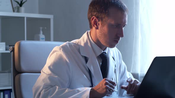 Professional medical doctor working in hospital office using computer technology.