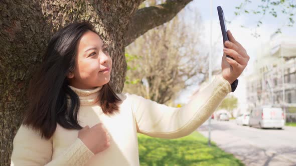 Close up face of Asian black straight hair woman at a park and using her smartphone