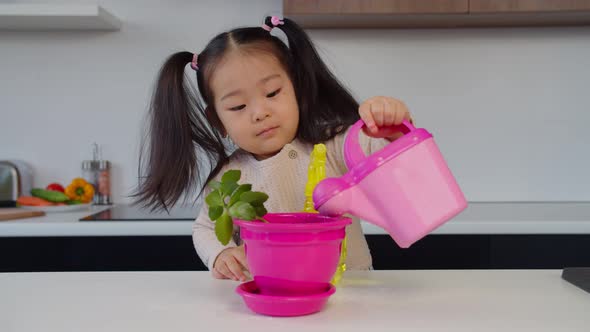 Portrait of Adorable Asian Toddler Girl Watering Plant