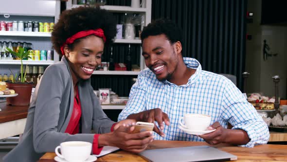 Man and woman interacting with each other while having cup of coffee