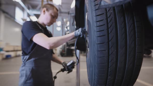 A Mechanic at a Car Service Station Working with a Wheel