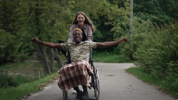 Joyful African American Man in Wheelchair Stretching Hands Smiling As Cheerful Caucasian Woman