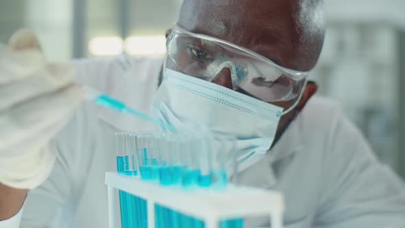 African American Scientist in Mask Doing Experiment in Laboratory