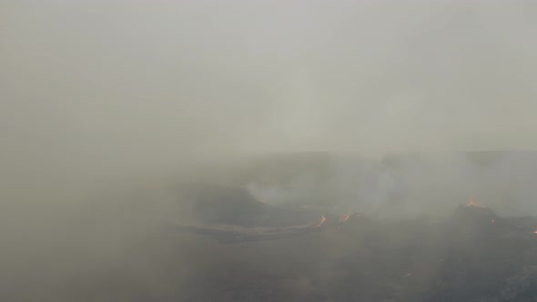 Aerial drone view through smoke revealing people at a volcano basin