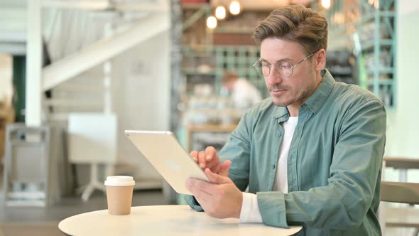 Serious Professional Middle Aged Man Using Tablet in Cafe 