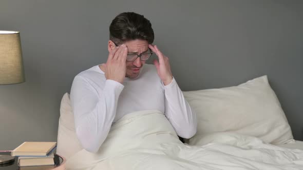 Stressed Middle Aged Man with Headache in Bed