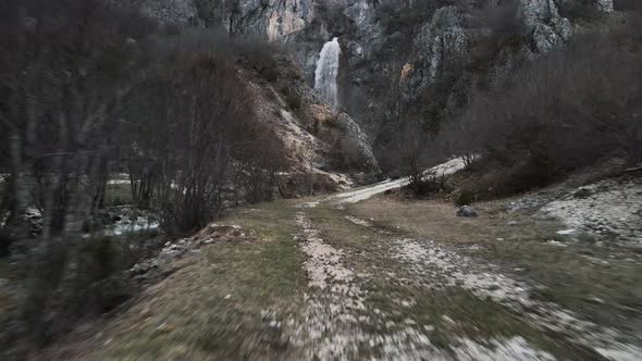 Drone flying fast through a path towards the Skakavic waterfall in Albania.
