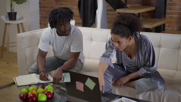 Wide Shot of Young African American Couple of Startupers Planning Business in Home Office in the