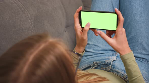 Woman sitting on a couch with Green Screen Smartphone