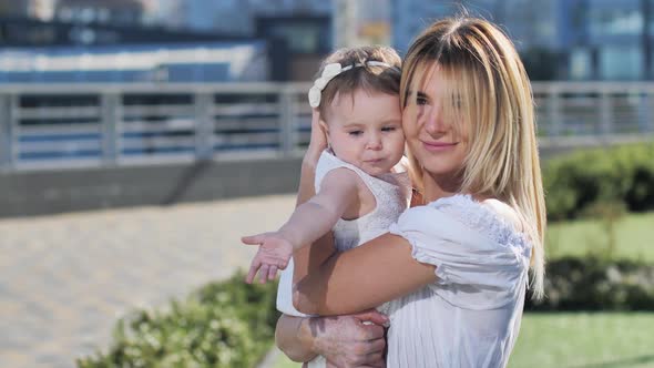 Loving Mother Hugging and Kissing Baby Outdoors