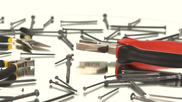 Gray and Red Pliers and Gray, Yellow Round-nose Pliers on White Among Nails, Reflection, Rotation