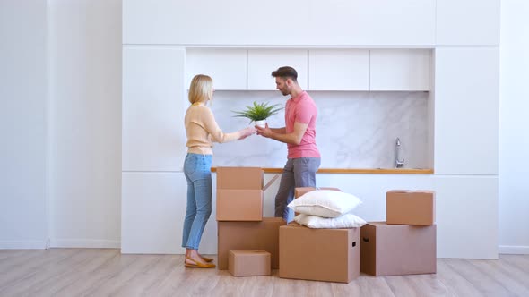 Romantic couple in love takes pot plant and glasses out of brown cardboard box