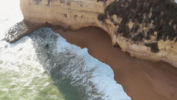 Golden beach and rock outcroppings in Carvoeiro, Algarve, Portugal - Descent Aerial shot